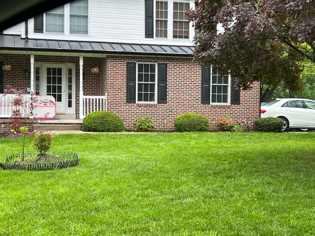 Brick colonial home with new standing-seam metal roof and black shutters