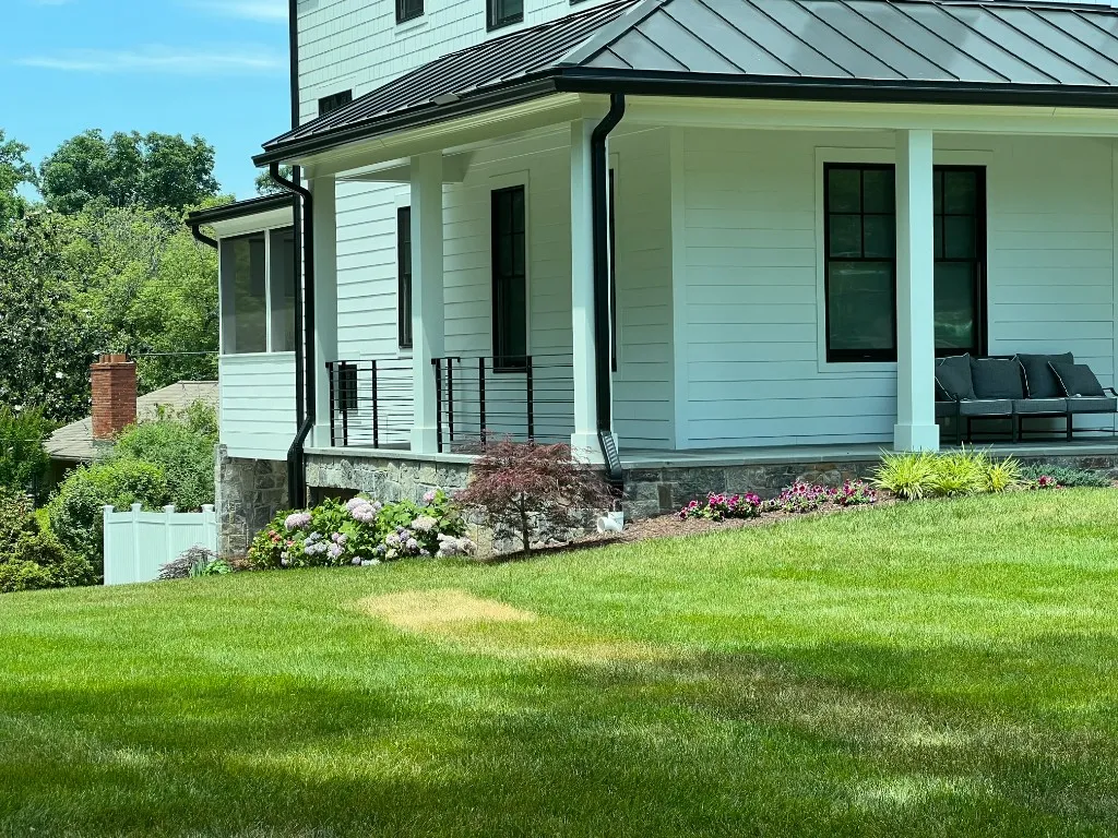 White farmhouse with standing-seam metal roof, black accents, and covered front porch